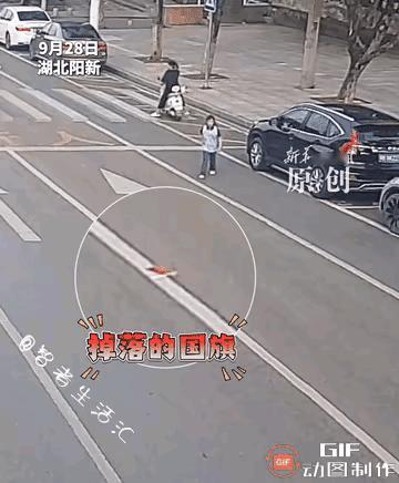 女孩看到落在马路中间的国旗，首先想到的就是要把这面国旗捡起来，根本就没有想到来往
