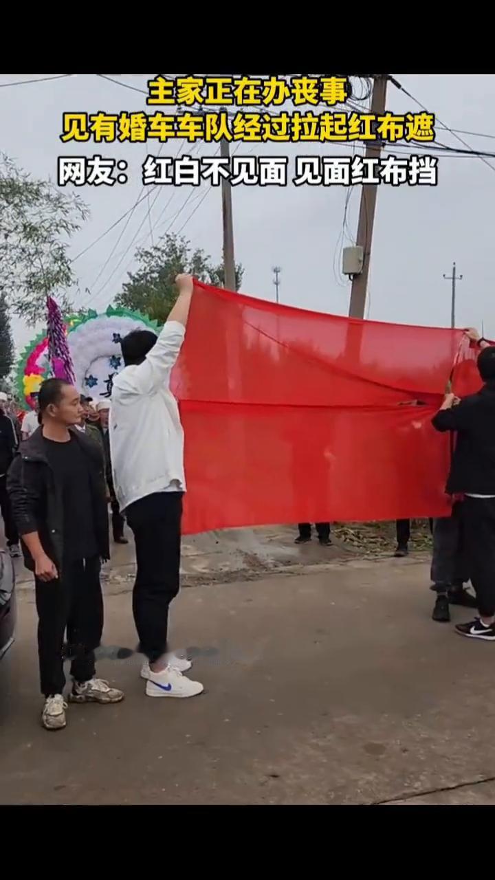 主家正在办丧事，见有婚车车队经过拉起红布遮。网友：红白不见面，见面红布挡。
10