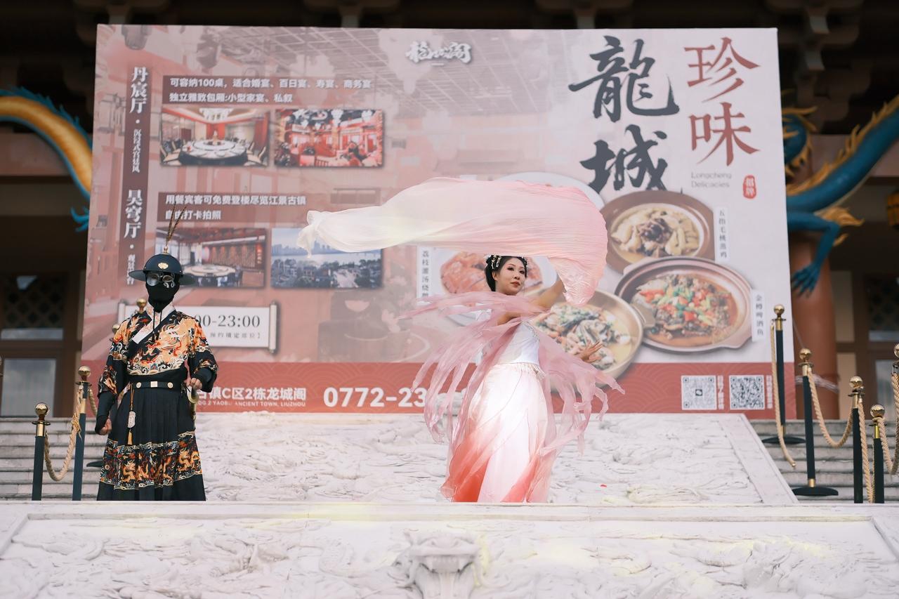 古镇的黃昏，粉衣女子表演舞姿。凑合看热闹的人多国风盛宴 体验穿越千年的古风之美 