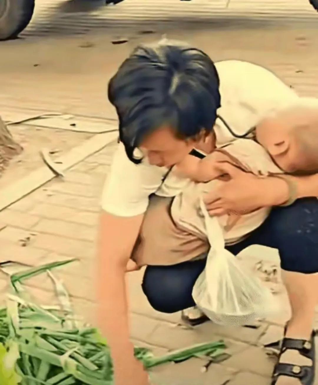 太心酸了！一名女子在下班路上意外看见一名中年女子抱着孩子，在捡路边的烂菜叶。那些