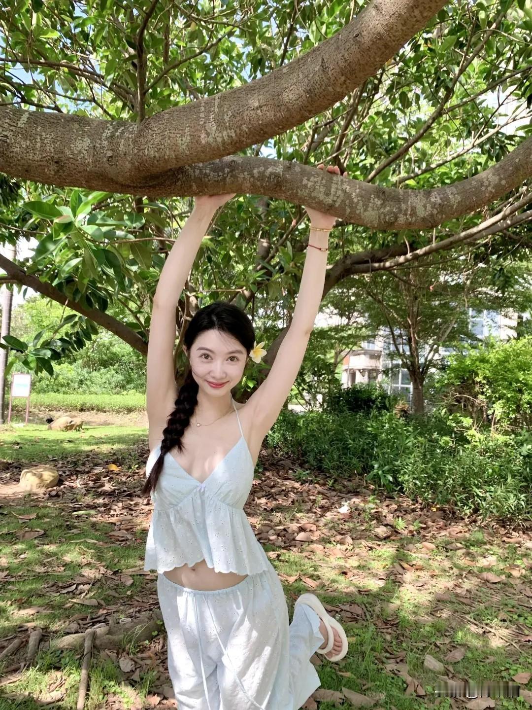 枝桠横空揽翠光，
佳人含笑倚苍桑。
素衣轻飏风微漾，
单辫垂丝蕊暗香。
皓腕高擎