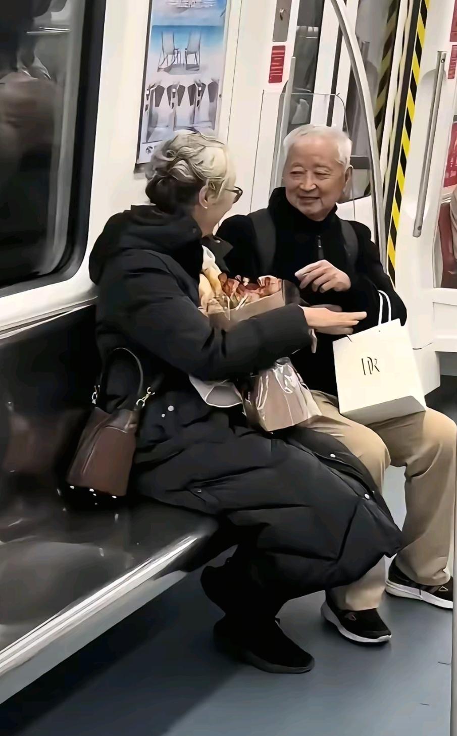 一对老年夫妇相互搀扶着进入地铁车厢里，大爷轻揽着大妈的胳膊，大妈手搭在大爷的手腕
