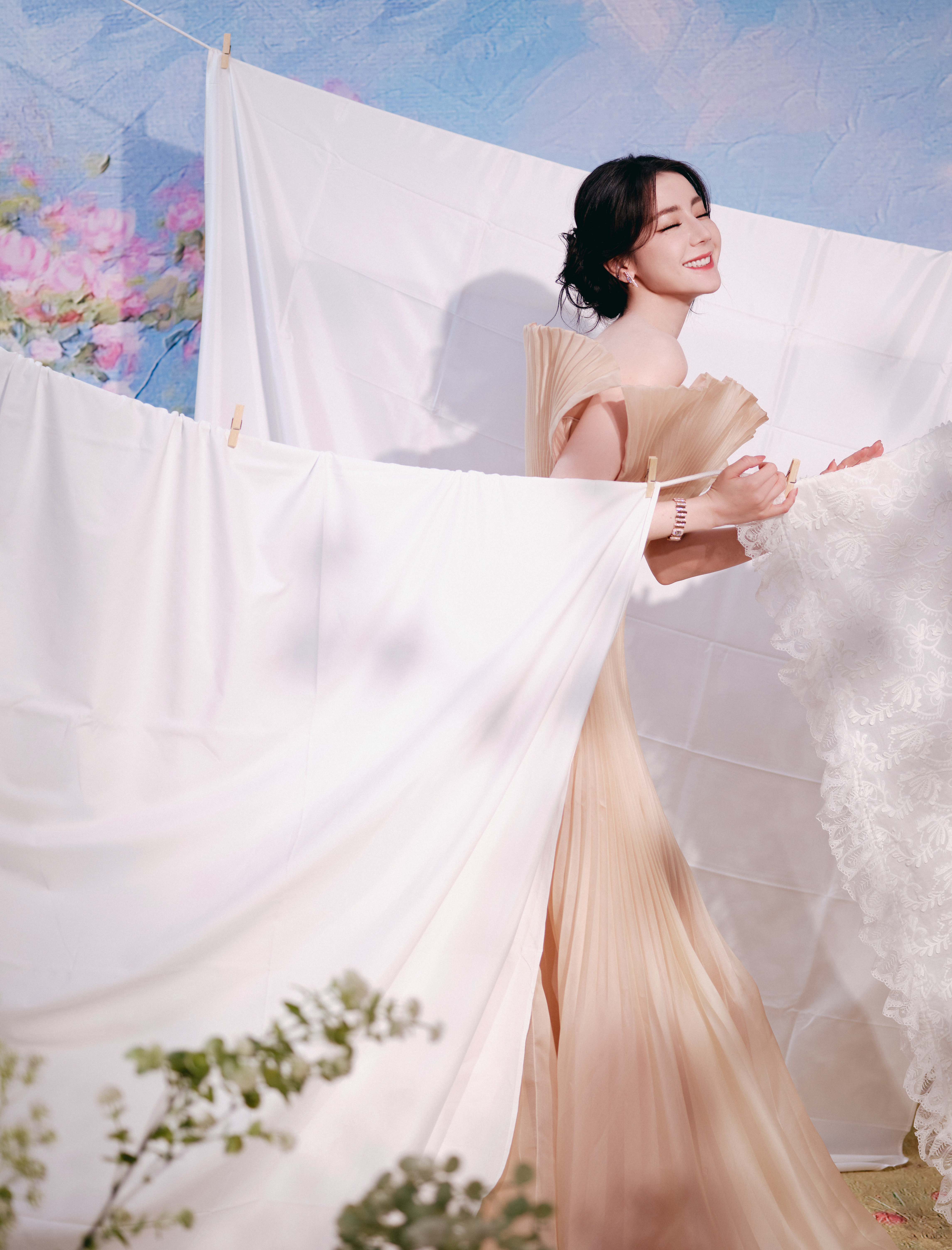 迪丽热巴 裸色纱裙晕着柔光，荷叶边肩线勾勒优雅，手捧花簇轻垂，眉眼低垂的瞬间，是