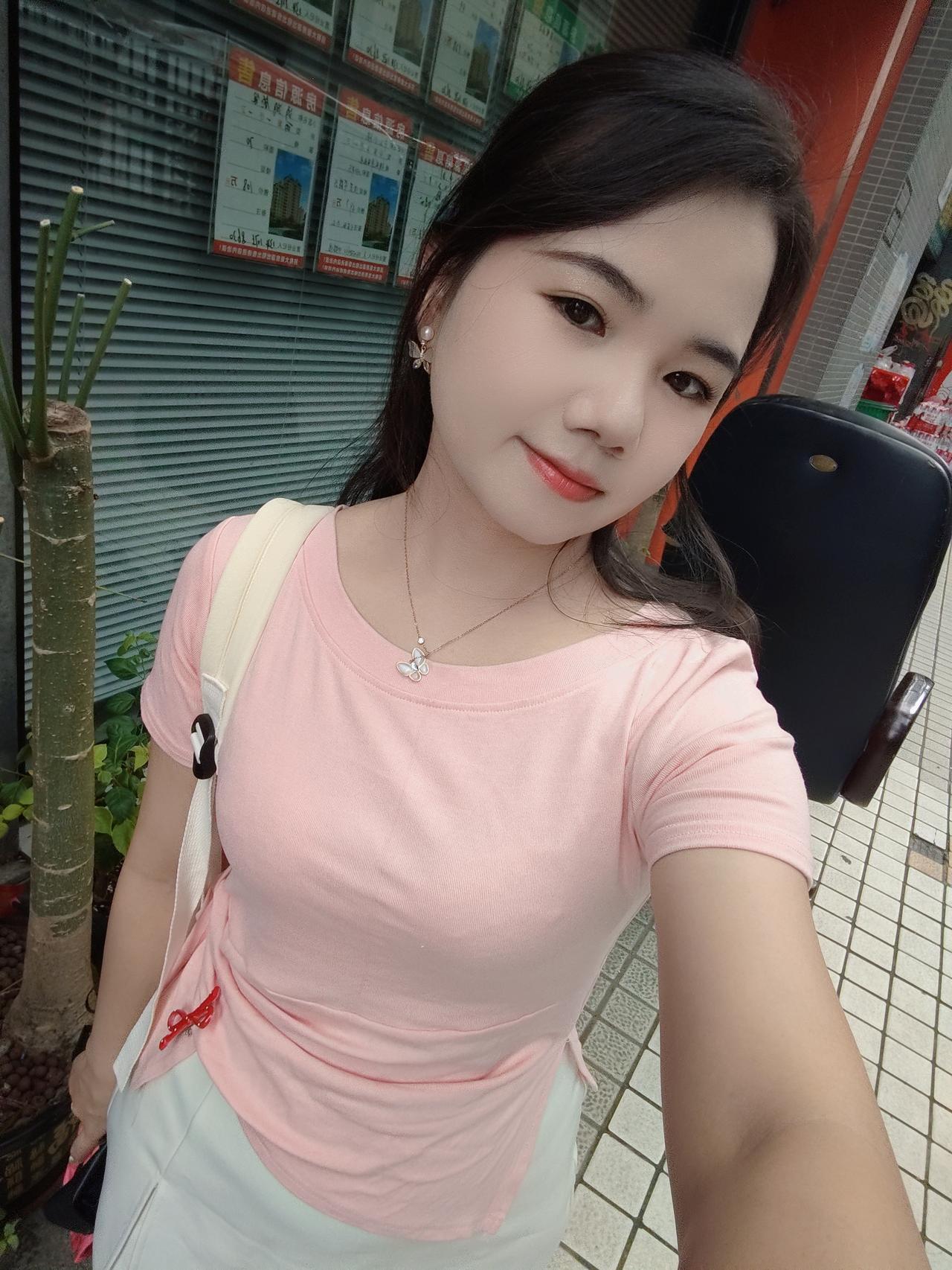 穿粉色T恤，背着包的女子自拍。