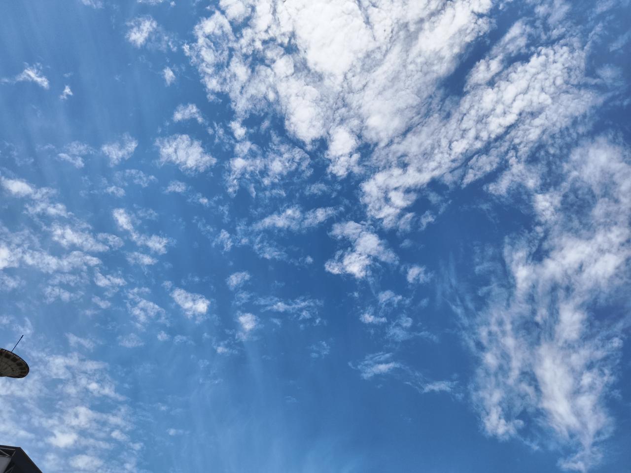 画面左下角的天线和建筑一角，成了这片天空最温柔的“边框”，把这份辽阔的惬意框了进