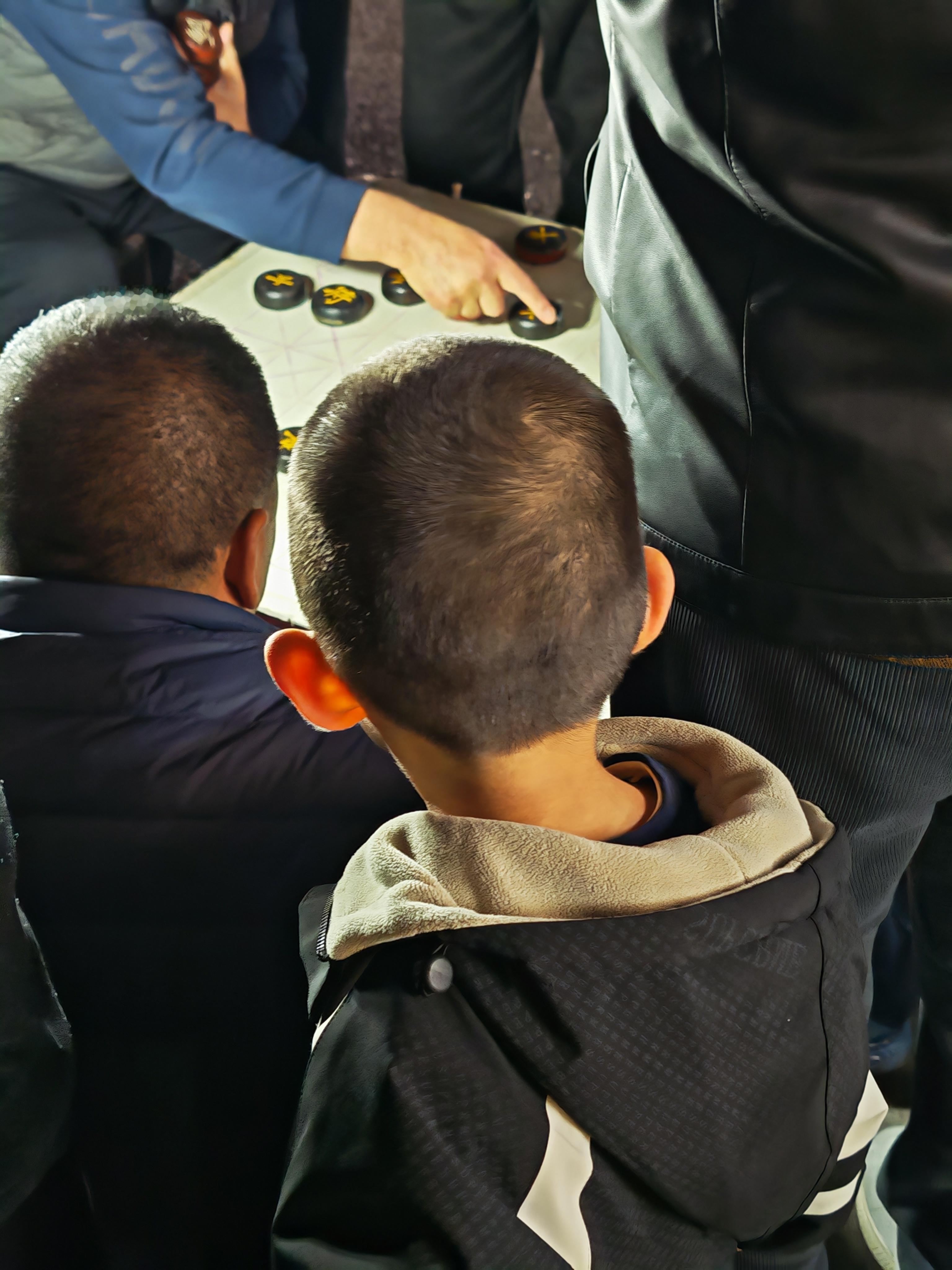 这小子象棋瘾有点大，在路边看下棋，叫不回家了。