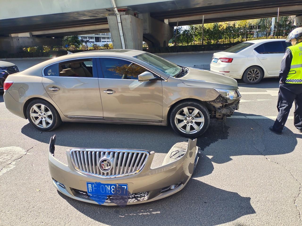 东二环快速路下边，小轿车拐弯，前面那辆救援车直行，就把车头前面这一大块刮下来了。