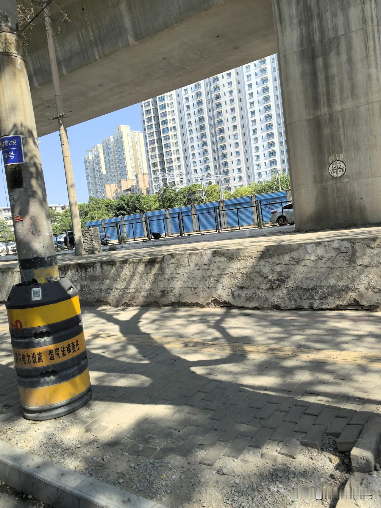 路面的水泥管堆了好多，好多石材散落地面。临空的高铁线下面，是裸露的水泥地面，部分