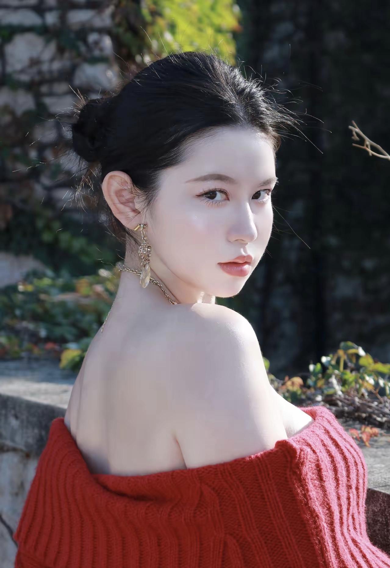 秋日暖阳下，红衣少女倚石而坐，耳畔轻风拂过，静谧而美好。