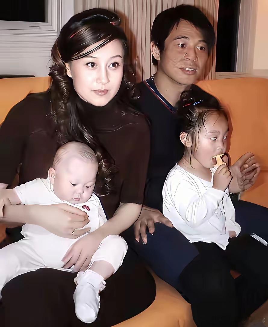 美人利智怀抱着刚出生不久的小女儿，李连杰则抱着大女儿一同拍摄的照片。彼时42岁的