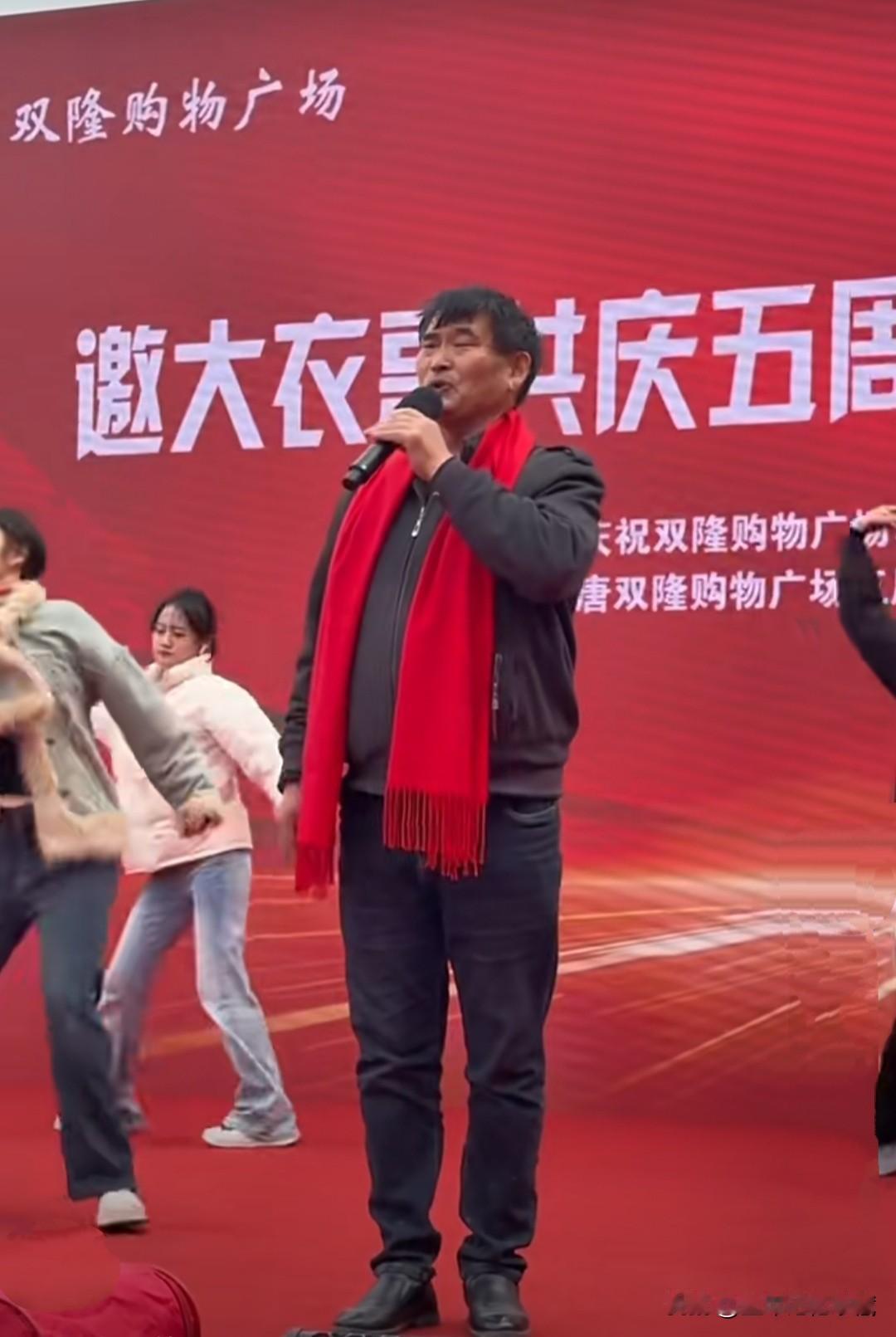 大衣哥朱之文挂着红围脖在聊城演出，大衣哥朱之文越来越时尚了，皮鞋牛仔裤，时尚夹克
