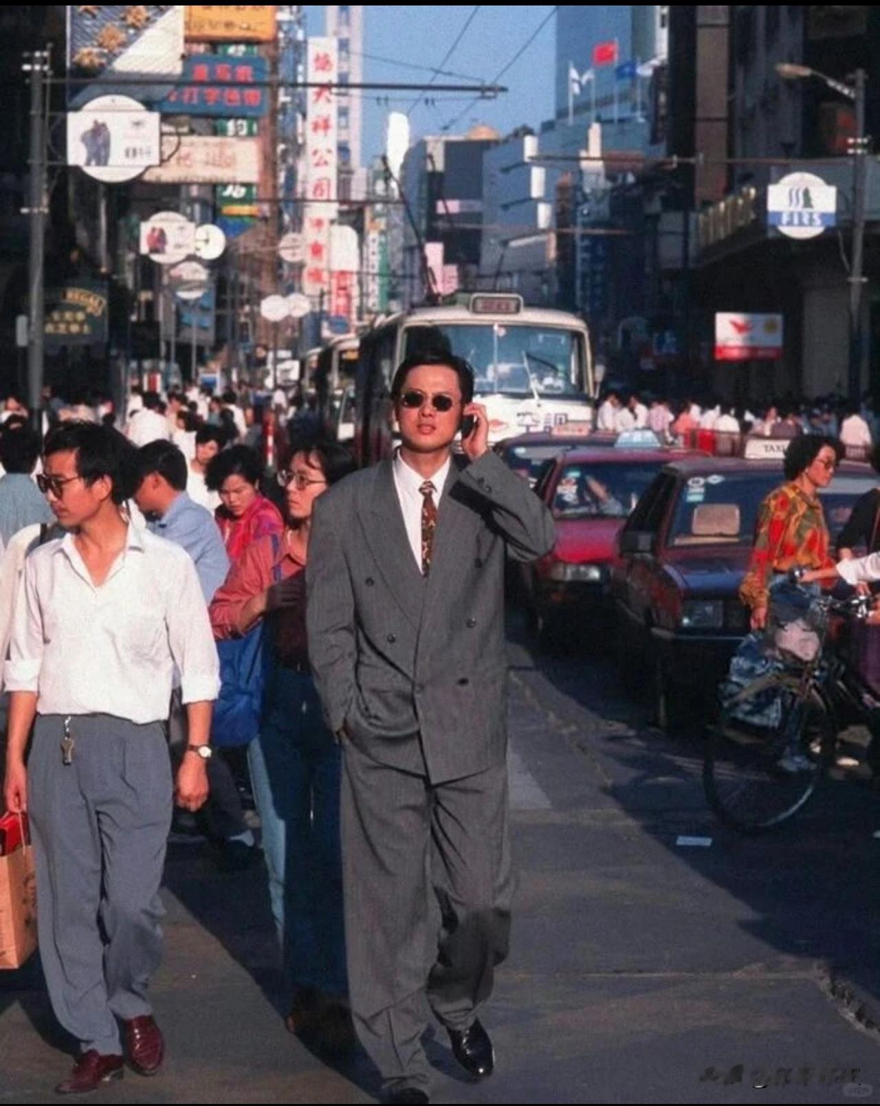 老照片欣赏： 这照片摄于1995年，我国某地街头随拍；

画面正中央的男子一身灰
