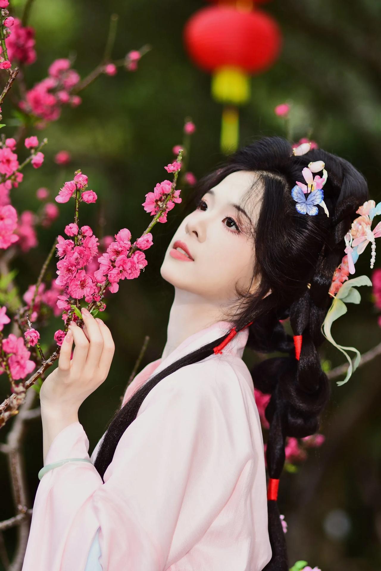 樱花树下，汉服美人手持花枝，粉嫩浪漫，宛如仙境。仙女下凡赏花开 花悔美女溶 花美