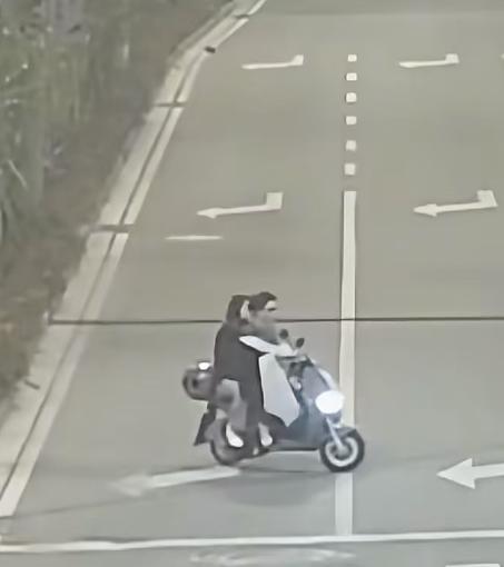 马路上，一对情侣骑着车，本该平稳匀速向前行驶，坐在后座的女子忽然探出身子，整个人