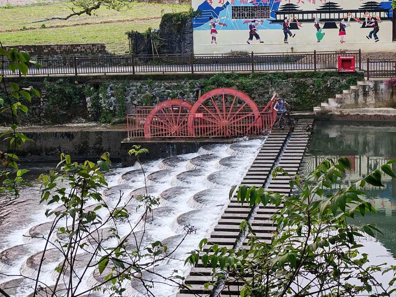 小溪潺潺，水车悠悠，仿佛时间在这里放慢了脚步。河边的绿树与倒影交织，像一幅静谧的