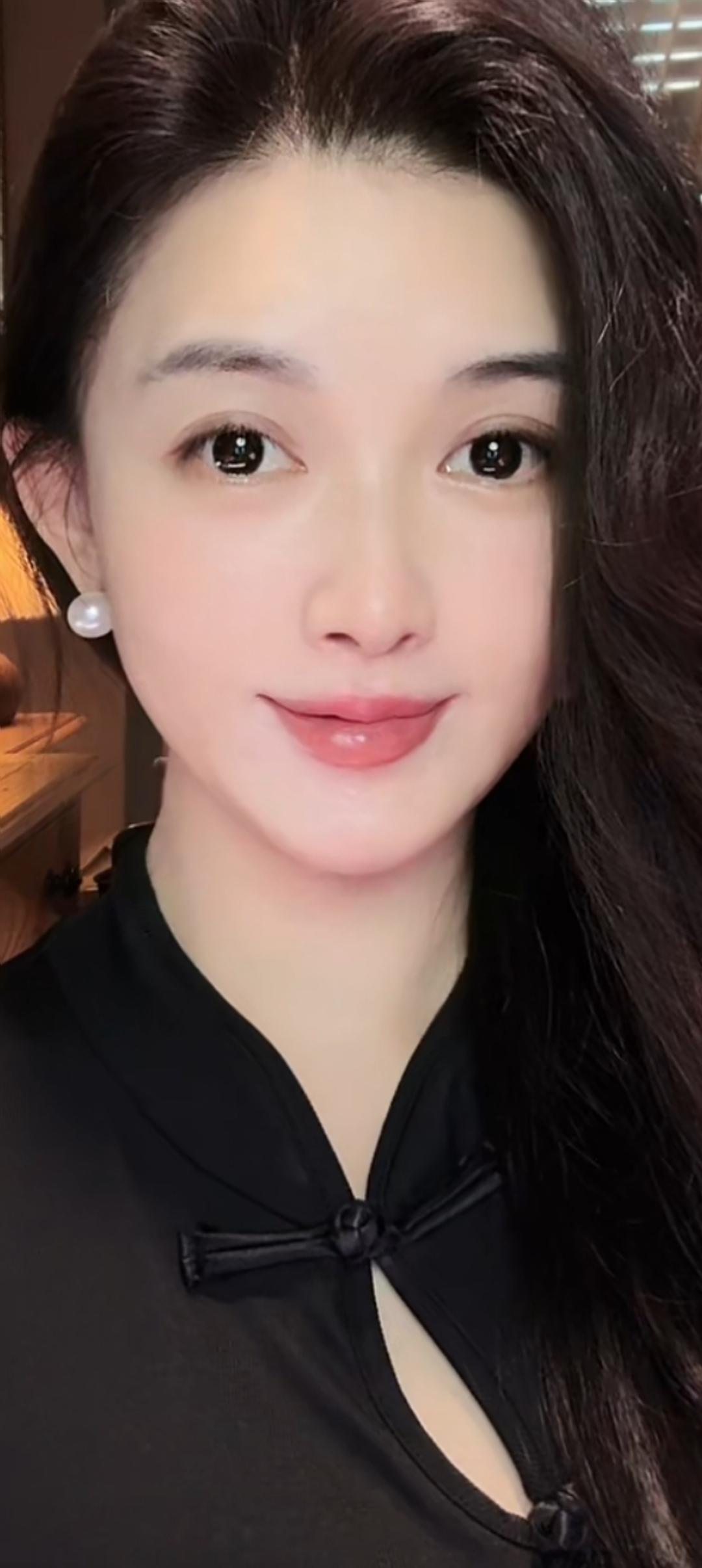 这位美女穿着黑色衣服，微笑着看镜头。