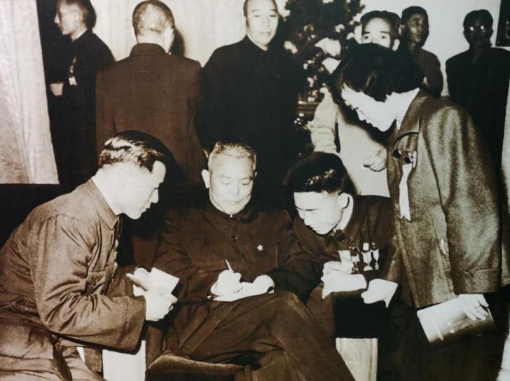1958年，国务院副总理兼财政部长李先念在人民大会堂，为青年积极分子签名。
