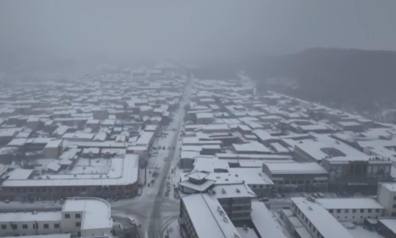镜头中，城镇被皑皑白雪尽数覆盖，雾气笼罩下更显苍茫。我国西北、西南等地雨雪天气频