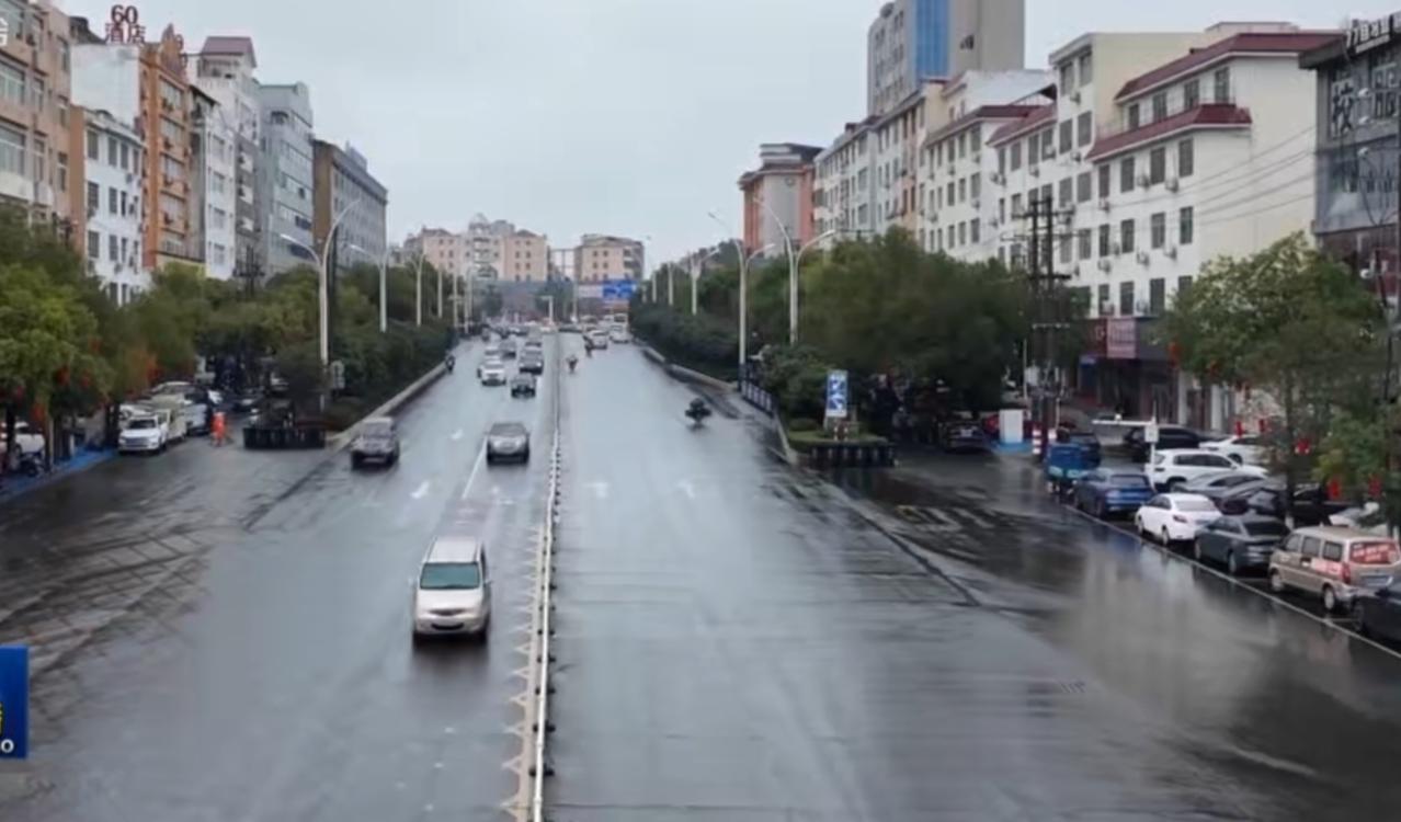 细密的雨丝笼罩着我国中东部的城市与道路，路面被雨水冲刷得油亮反光，车辆在湿滑的路