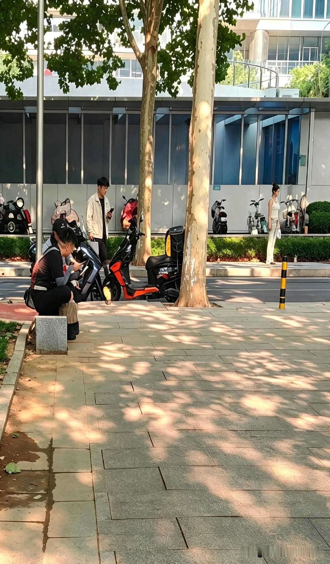街角同框：外卖小哥蹲地扒饭，女孩架机直播，谁在“收割”生活？

同一个街角。

