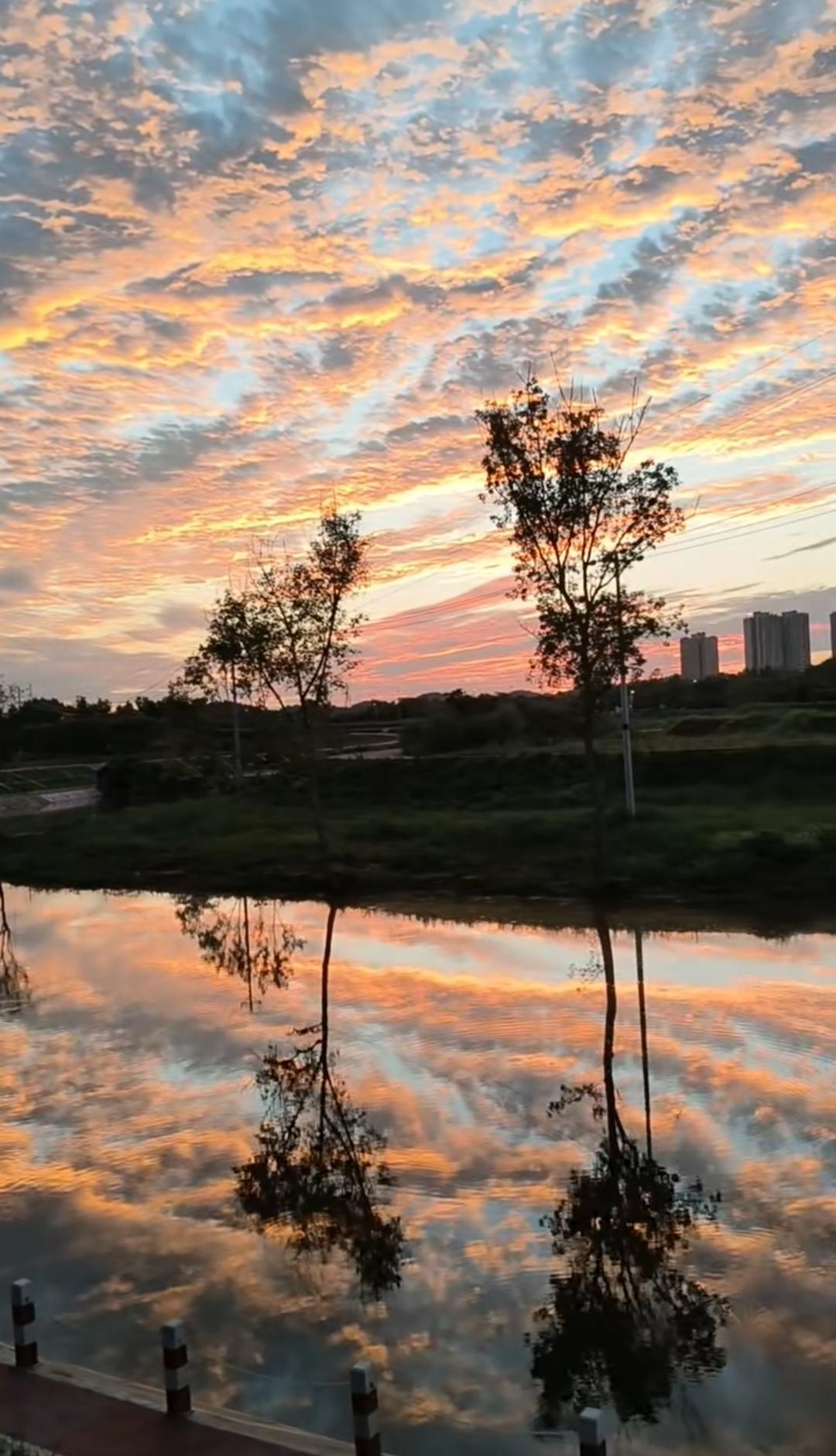 霞光倾洒，将整片天空尽数铺满，又清晰地倒映在平静的河面之上，水天相融，连成一片，
