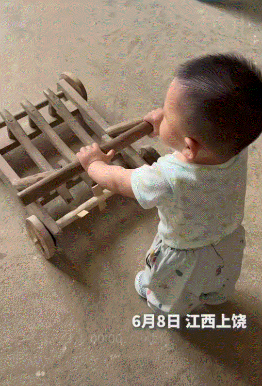 江西上饶，一位宝妈拍下自己宝宝推着家中一个陈旧木推车，在院子里开心学走路的一幕。