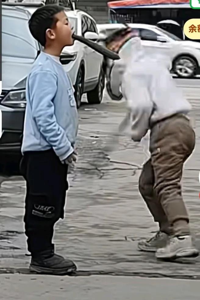 两孩子街头表演才艺，翻跟斗切黄瓜，小男孩嘴里叼着一根黄瓜，站在路上，女孩翻着跟斗