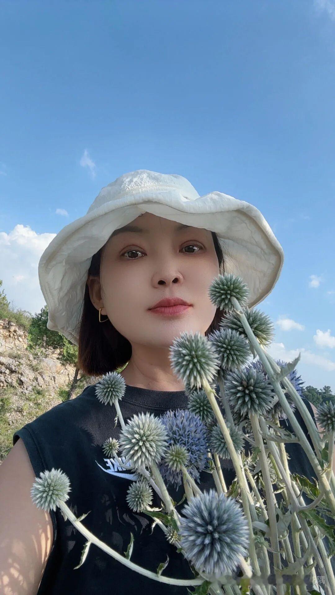 在蓝天白云下，拿着花自拍。