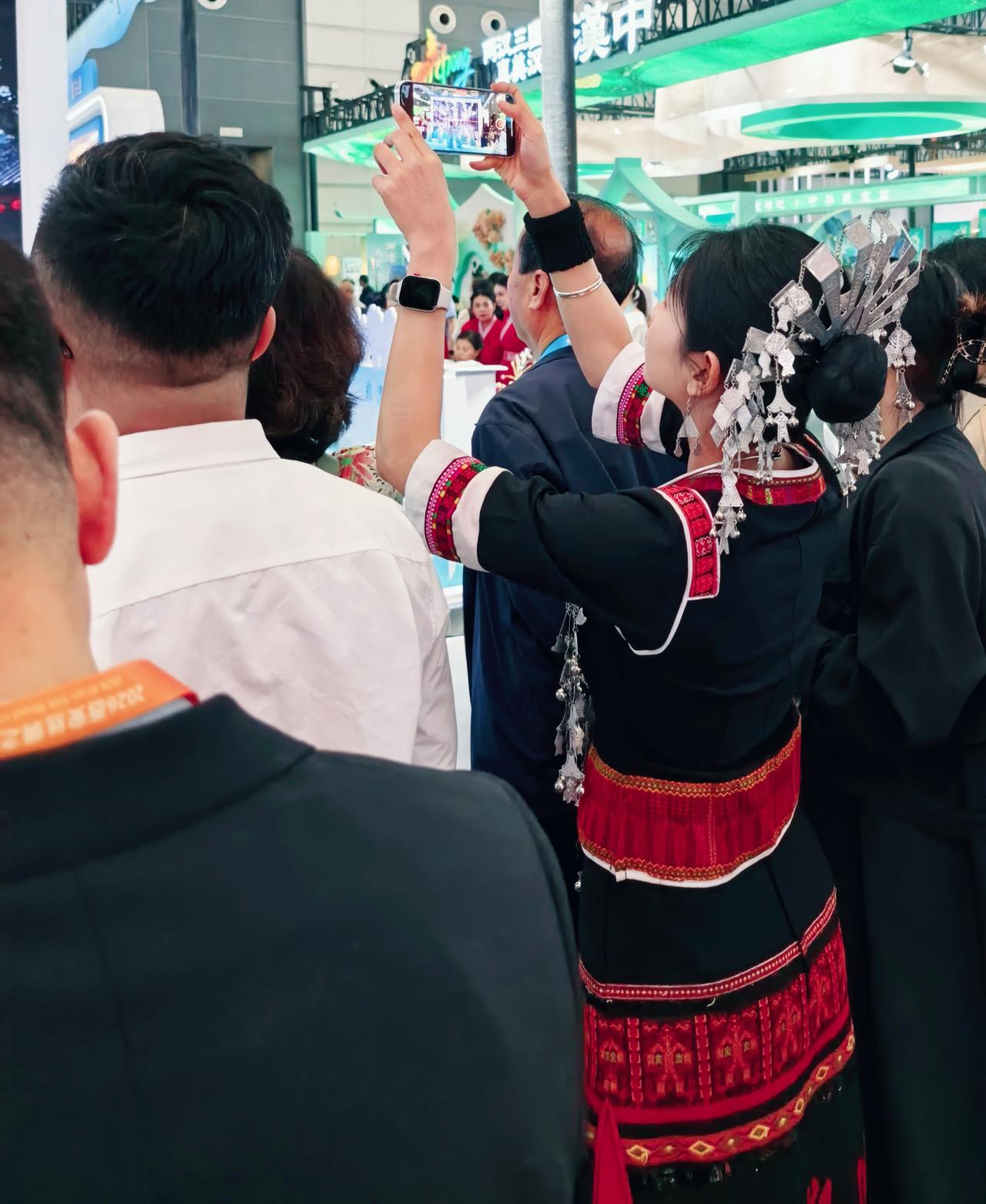 她发髻的银饰叮咚作响，指尖却在荧屏里定格另一场狂欢。壮锦的红与黑爬上了朋友的九宫