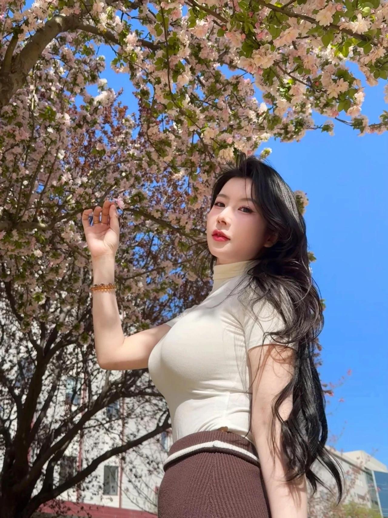 樱花树下，温柔少女轻抚花瓣，春意盎然。