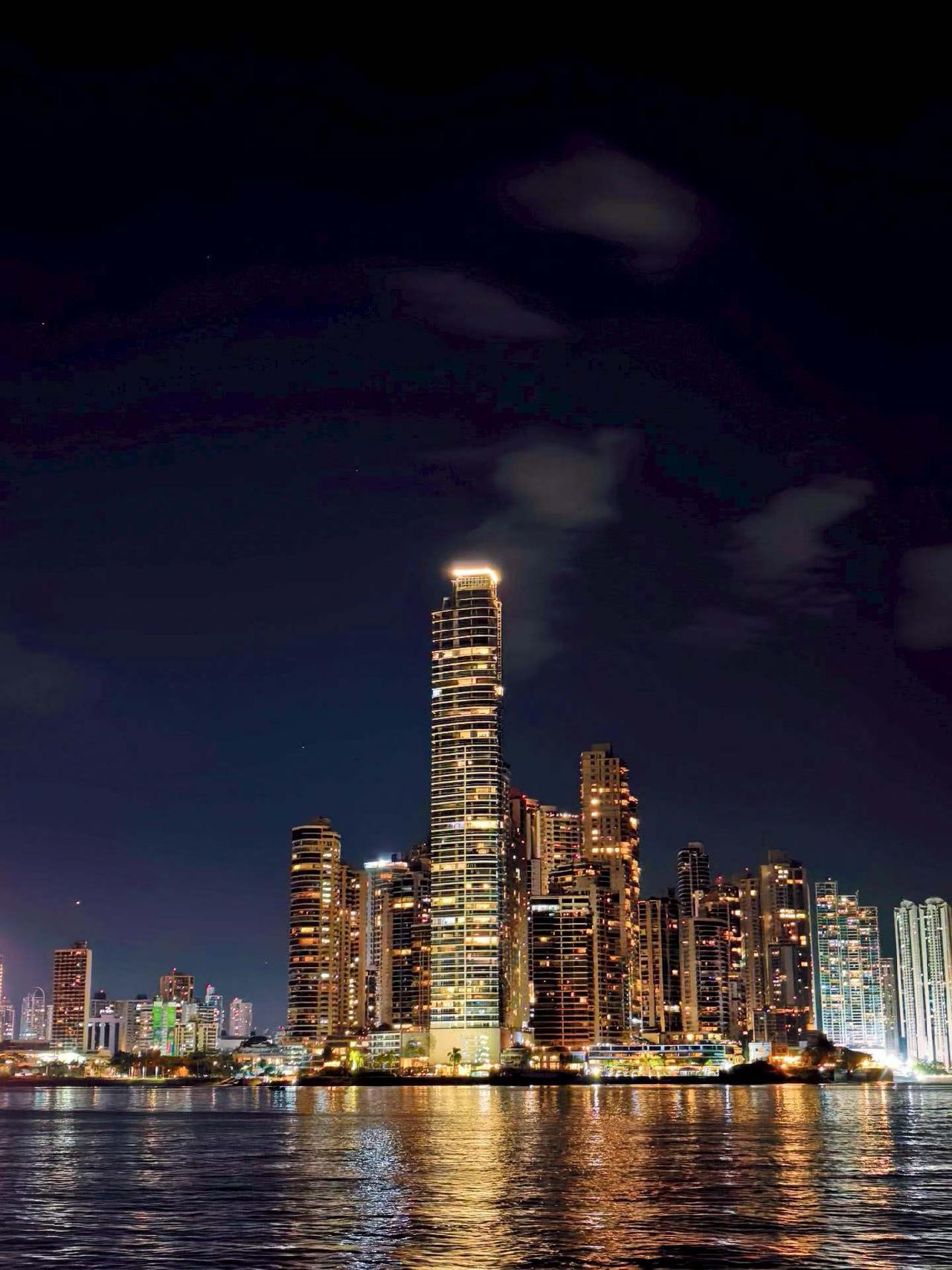 晒图笔记大赛多座现代化高楼林立，其中一座高耸的摩天大楼尤为醒目，顶部亮着暖黄色灯