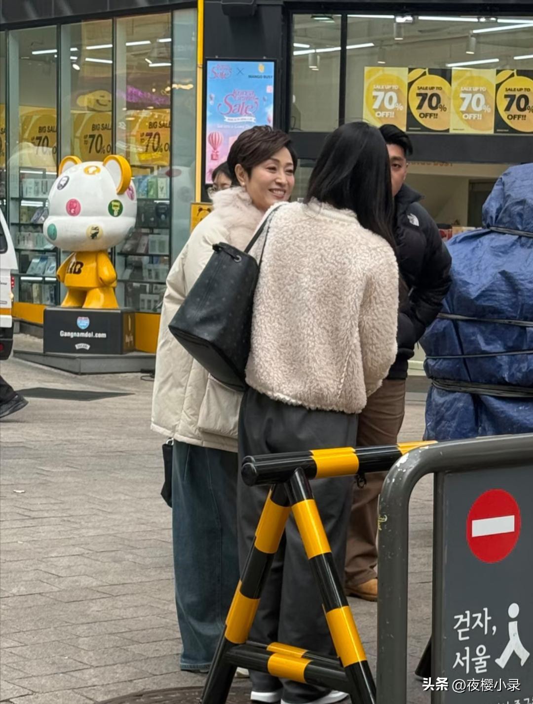 59岁陈法蓉和朋友现身韩国明洞街头，她穿着白色羽绒服，留着一头短发，真人看起来气