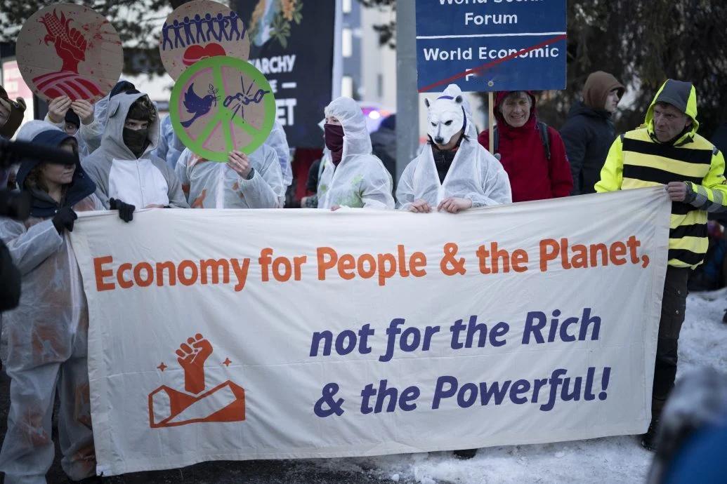 在瑞士达沃斯世界经济论坛场外，示威者手持反巨富横幅，抗议富豪和权贵垄断财富。(欧