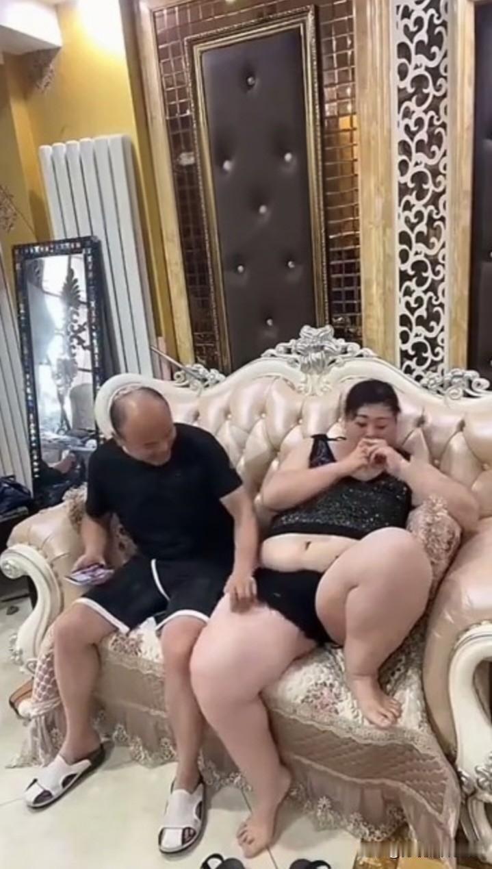 这情景十分逗趣。老公闲坐沙发，手脚不老实，一会儿捏捏老婆的腿，一会儿摸摸老婆的肚