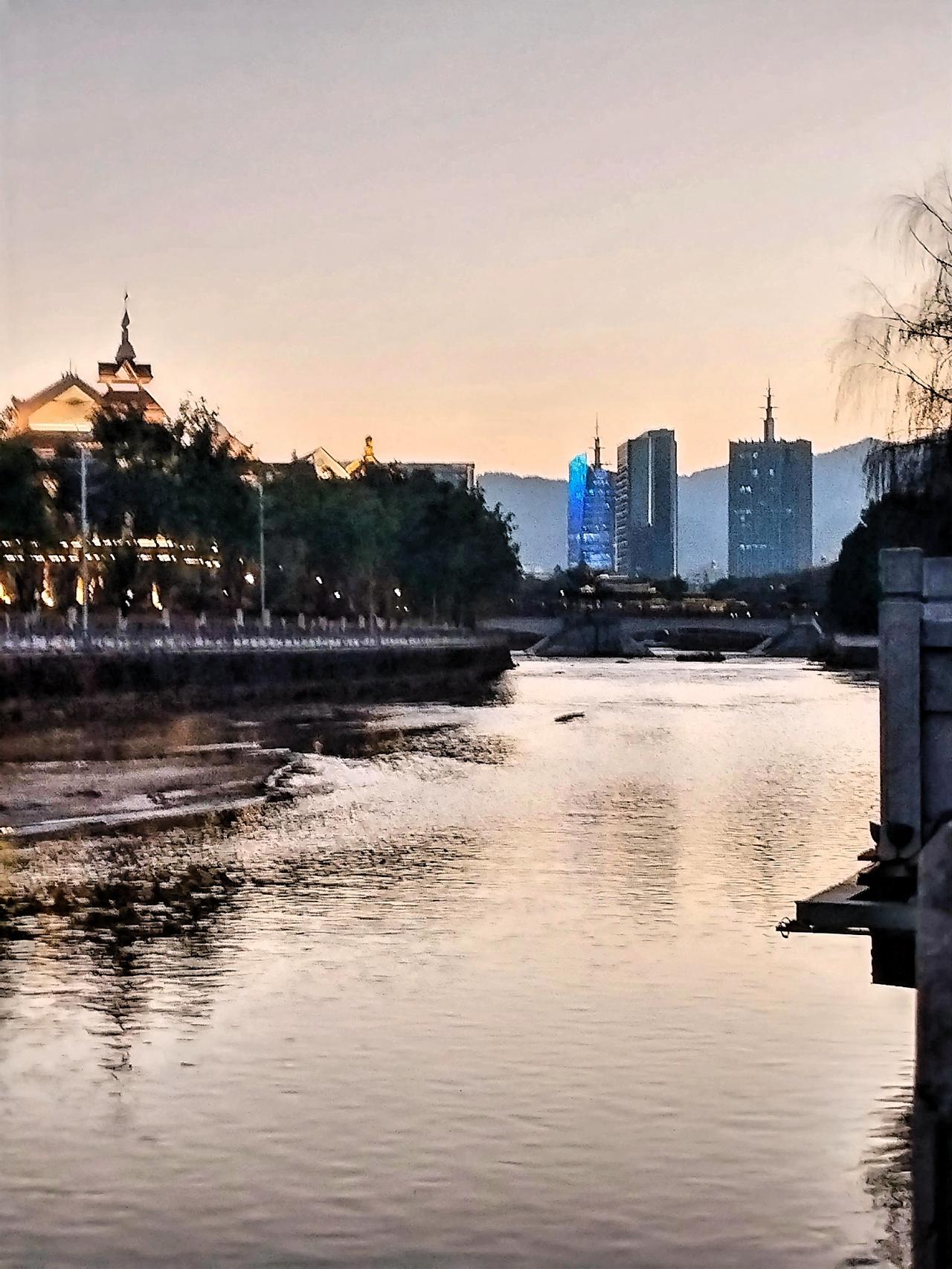 黄昏时分，静谧的河流映照着城市的灯火，仿佛置身于童话世界。粼粼波光中，灯光的倒影