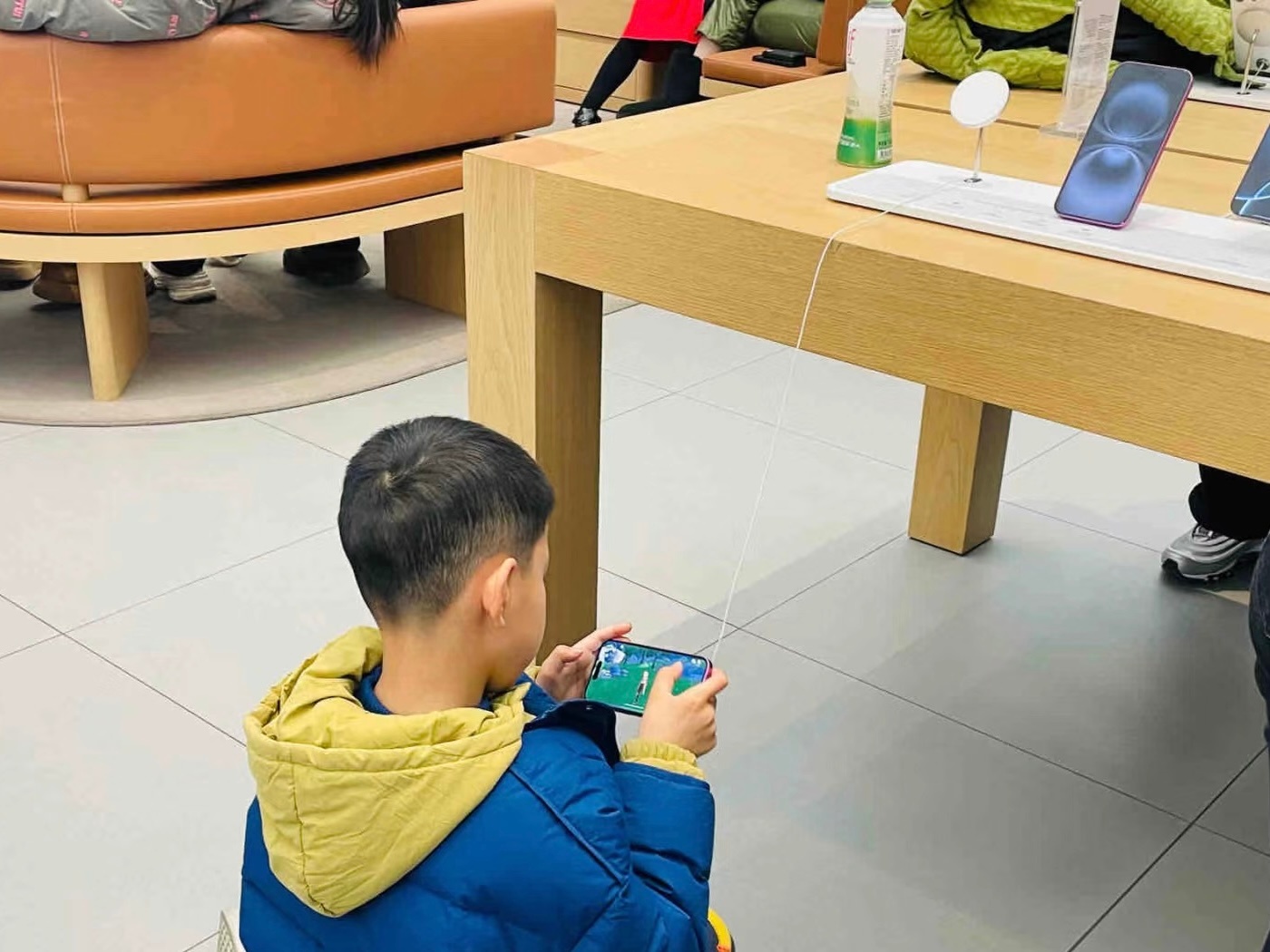 有小孩在 Apple store 拿样机打原神哈哈哈哈哈哈哈有趣 站着玩累了就坐