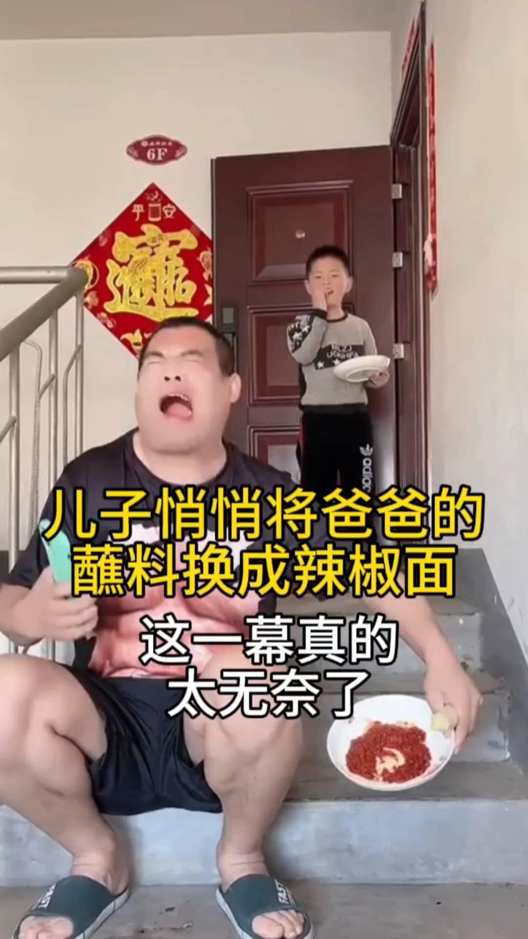爸爸坐在楼梯处，拿着大葱，然后看着手机蘸着酱料吃。儿子看到后悄悄把酱料换成辣椒面