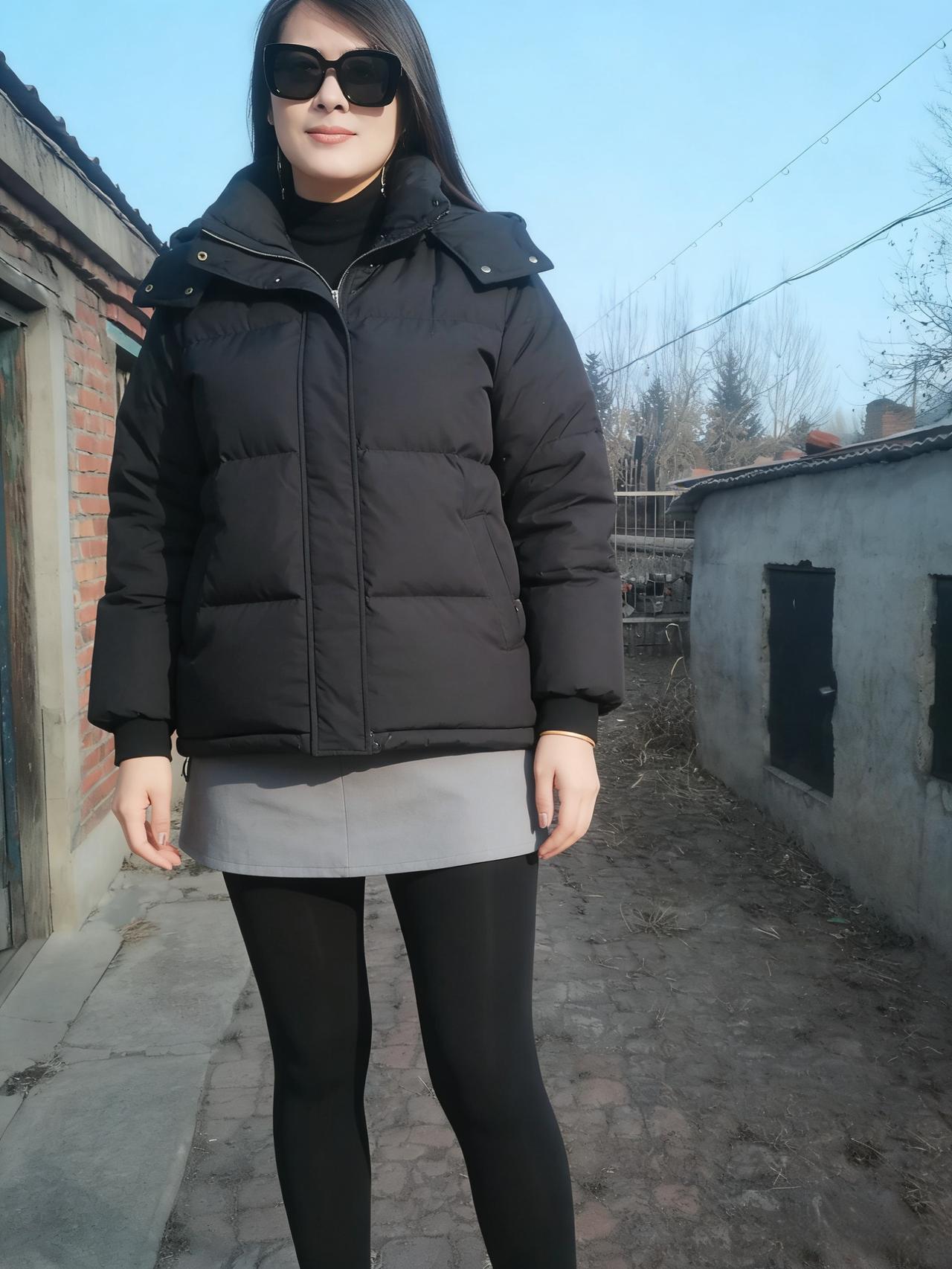 晴光泼在老旧的院墙，
红砖的纹，混着水泥的凉。
她立在巷陌的中央，
黑羽绒的厚，