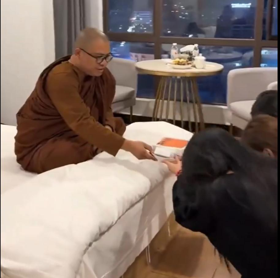 豪华酒店房间内，一和尚坐在床上，
三个美女下跪拜佛，
并上贡手机一部。
至于后来