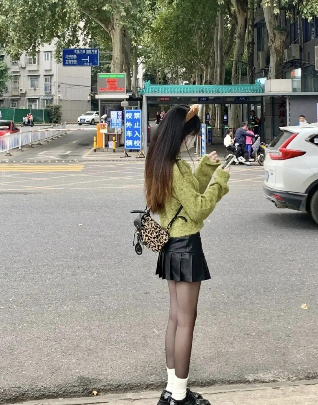 梧桐树荫裹着秋意，绿灯跳成倒计时。毛衣沾了点松针味，豹纹包晃着小叛逆，黑裙和长袜