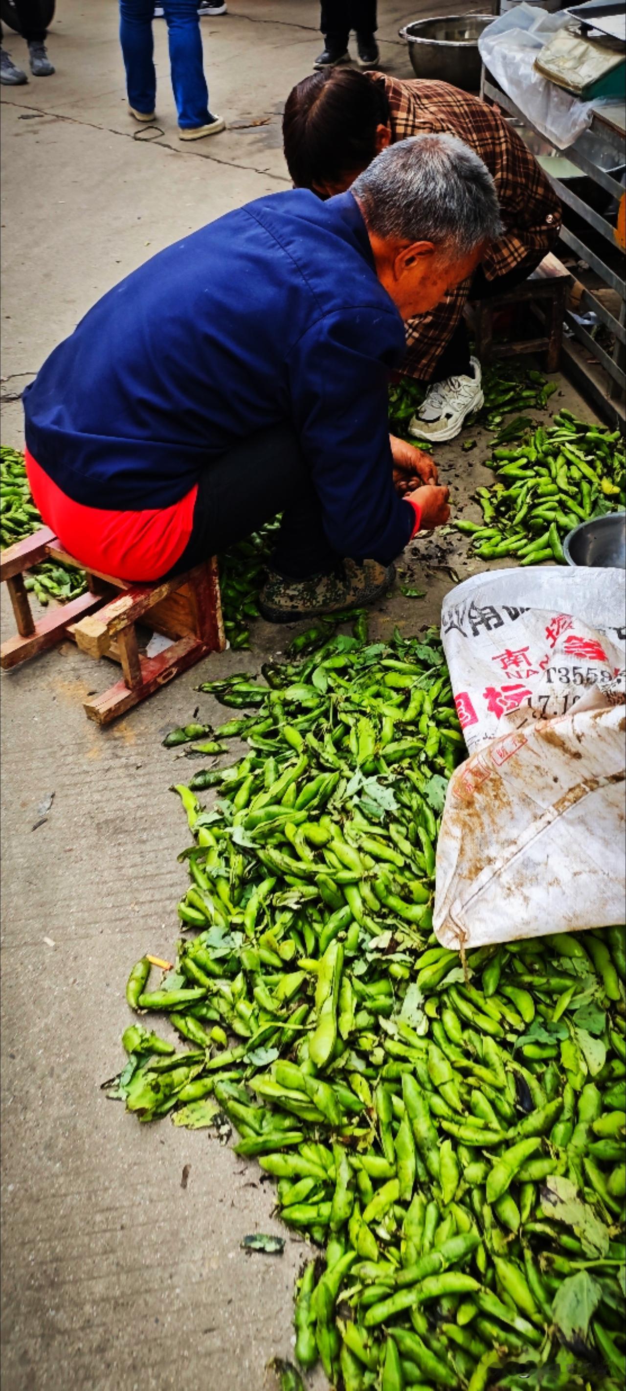 农贸市场里的胡豆很多，农户边剥边卖。本地人喜欢买了回去做一锅胡豆蒸饭，配点小菜就