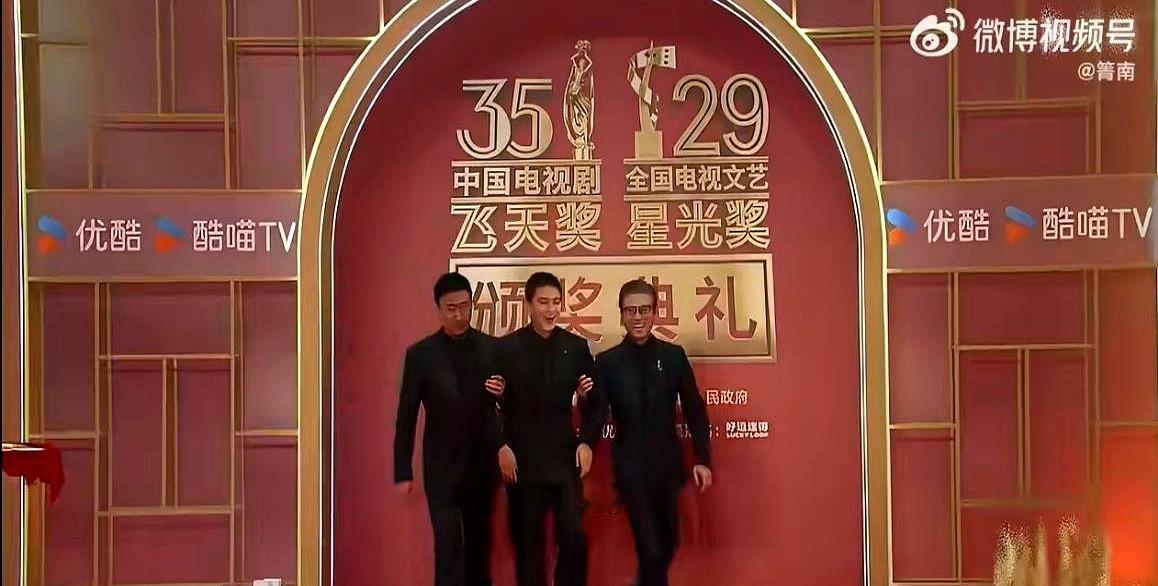 红毯上见过抢镜头的，真没见过老戏骨主动抢着给年轻后辈“当助理”的。

胡军和李乃文一左一右，直接把欧豪“架”着走上了红毯。欧豪夹在两个前辈中间，路都快不会走了。

到了签名板前更绝，欧豪刚签完字，李乃文顺手就极自然地把笔接了过去，胡军则在旁边背着手站着，眼神松弛得很。

台下快门响成一片，根本没人看