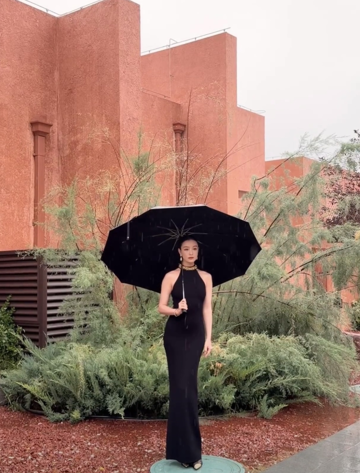 倪妮穿着黑裙，雨中打着黑伞，然后淡定的踩着井盖拍照。如果北方的朋友看到倪妮踩井盖，肯定要说她的，不可以踩井盖！！！