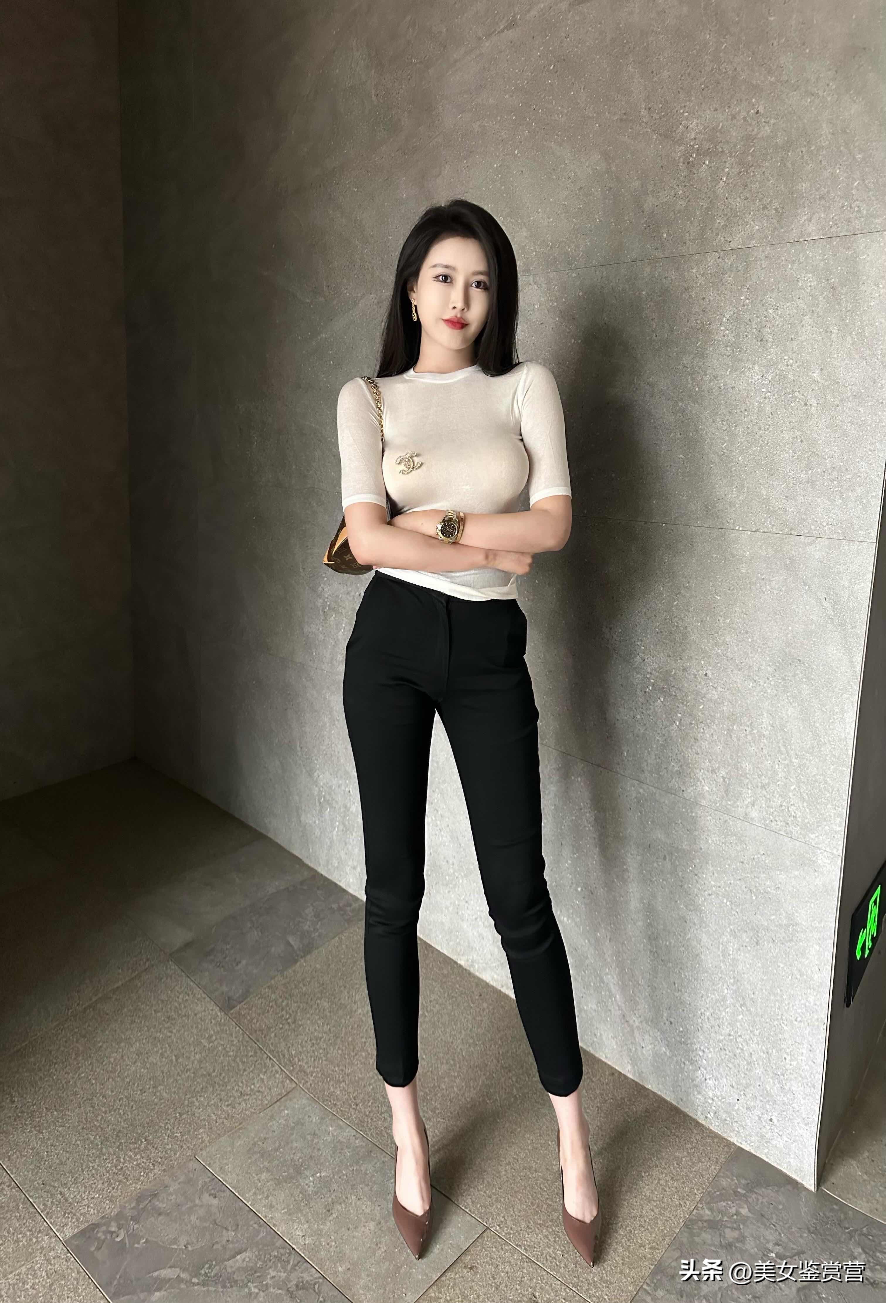 她站在浅灰色的墙面前，简约的空间衬出一身穿搭的精致。米白色的半袖针织衫...