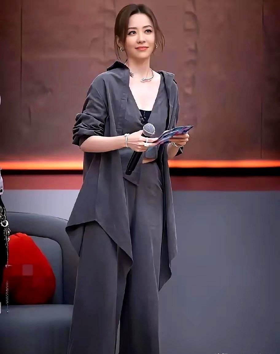 张靓颖往舞台上一站，没穿镶钻礼服，一身冷冽的高级灰直接控场。

不规则剪裁的灰色外套随意搭着，同色马甲叠穿黑色打底。她单手握着麦克风，眼神定在台下，垂坠的阔腿裤脚随着走动带起一阵风。

以前女明星总爱拼华丽，现在真正有底气的人早就不玩那一套了。越是极简的颜色和利落的线条，越能逼出骨子里的从容。没有乱