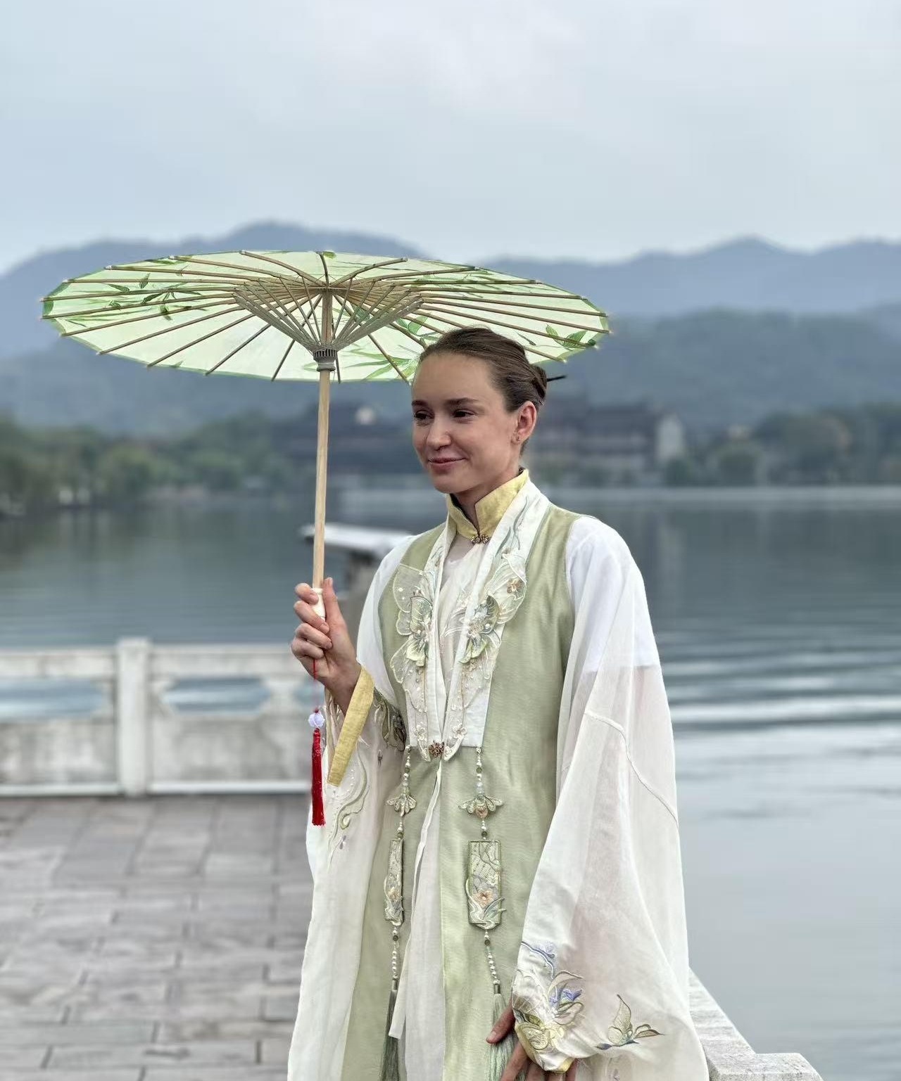谁能想到，莱巴金娜一组宁波东钱湖写真，能把“淡颜古装”的讨论度直接拉满？照片里她站在湖边青石板上，雨雾还没散，衣角被风轻轻掀起，像刚从江南画里走出来。

刚在办公室摸鱼刷到，同事端着奶茶凑过来：“这真是那个打球特别狠的娜娜？”说实话，这种反差太抓人了。赛场上她是硬碰硬的顶级选手，写真里却有种松弛感，