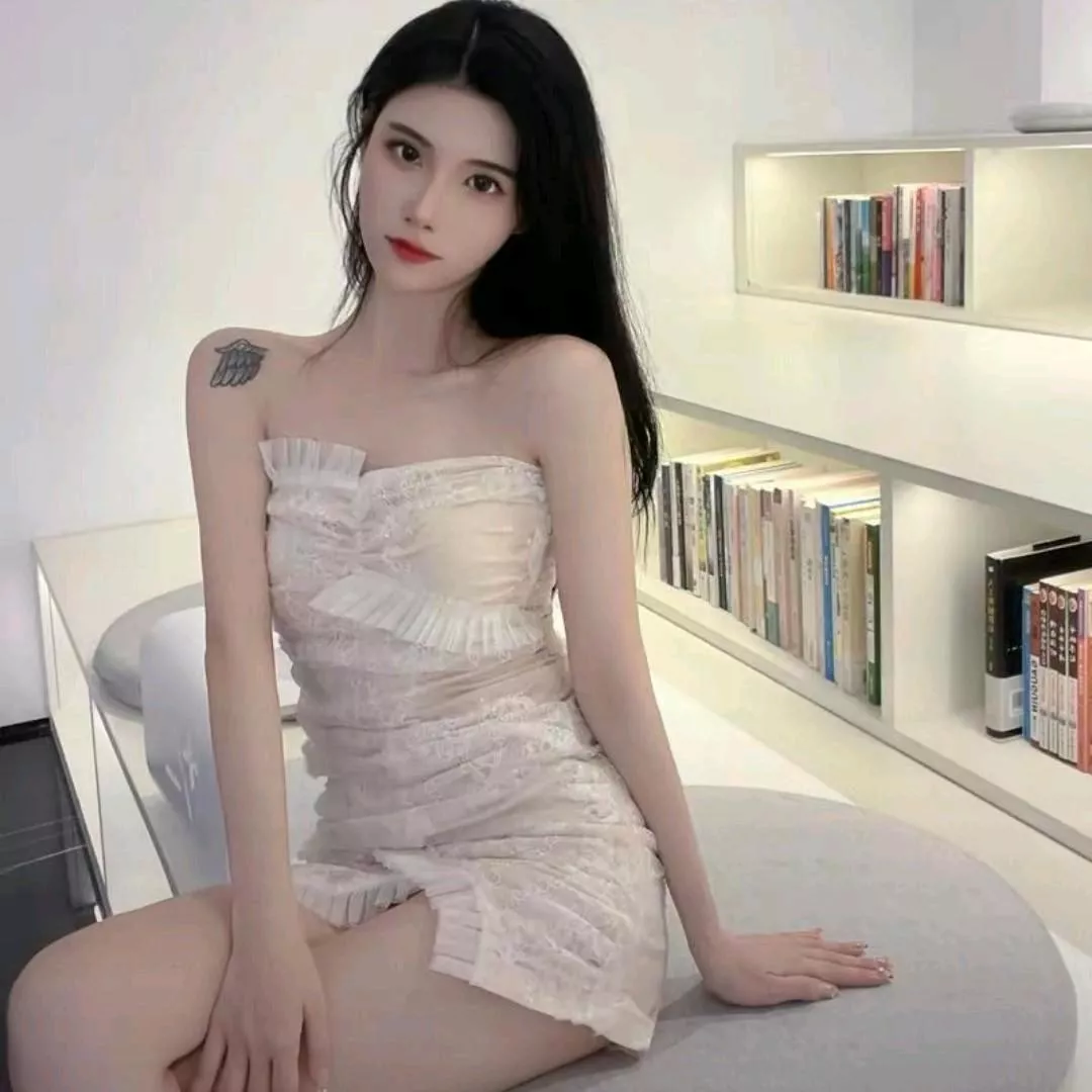 优雅黑发美女，穿着白色蕾丝礼服，坐在现代简约的书架旁，散发着高贵与神秘。