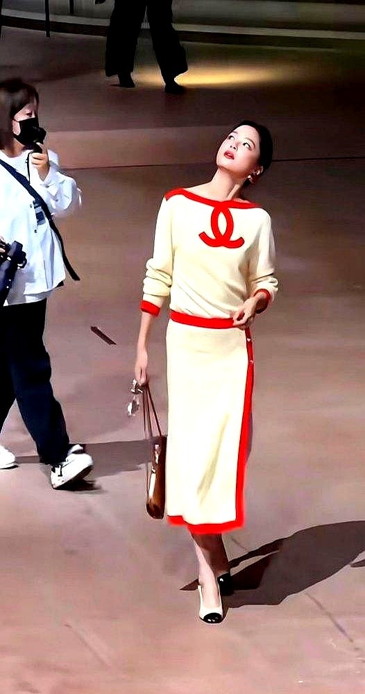 鞋跟后头空出大半截，踩着大一码的高跟鞋，辛芷蕾在巴黎香奈儿大秀上走得四平八稳。

第四次给品牌站台，直接穿走秀款超季早春，米白高开衩配正红滚边，架着副金属方框墨镜。外媒无修图怼脸生图出来，骨相锋利，眼神一点没飘，直接被网友评成全巴黎最有腔调的东方大女主。

刚斩获威尼斯影后，下一步戏又定了好莱坞的黄