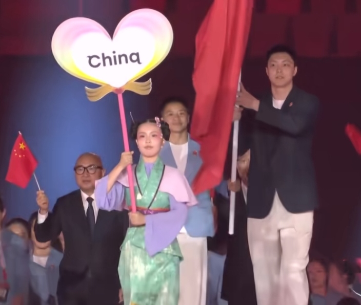 名古屋亚运会开幕式的一幕，看完心里颇有感触。
 
中国队代表团一身利落的运动服走过赛场，前方引导员的服饰带有东方交领的设计元素，两者放在一起，网上瞬间吵开了。
 
不少网友看到这一幕内心五味杂陈。源自华夏的服饰审美元素，出现在异国的体育赛场，难免会触发我们的文化共鸣。
 
但我们要厘清一件事：引导员