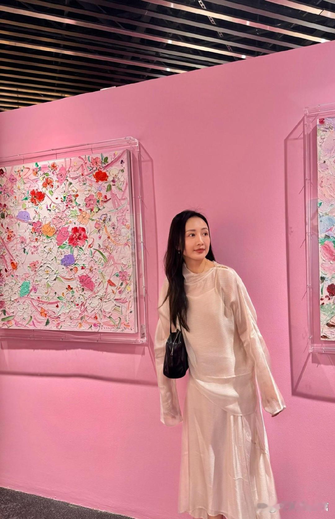 王鸥置身粉色花海，静立画作一侧，温和笑意映着满园春花，留下浪漫春日瞬间 ​